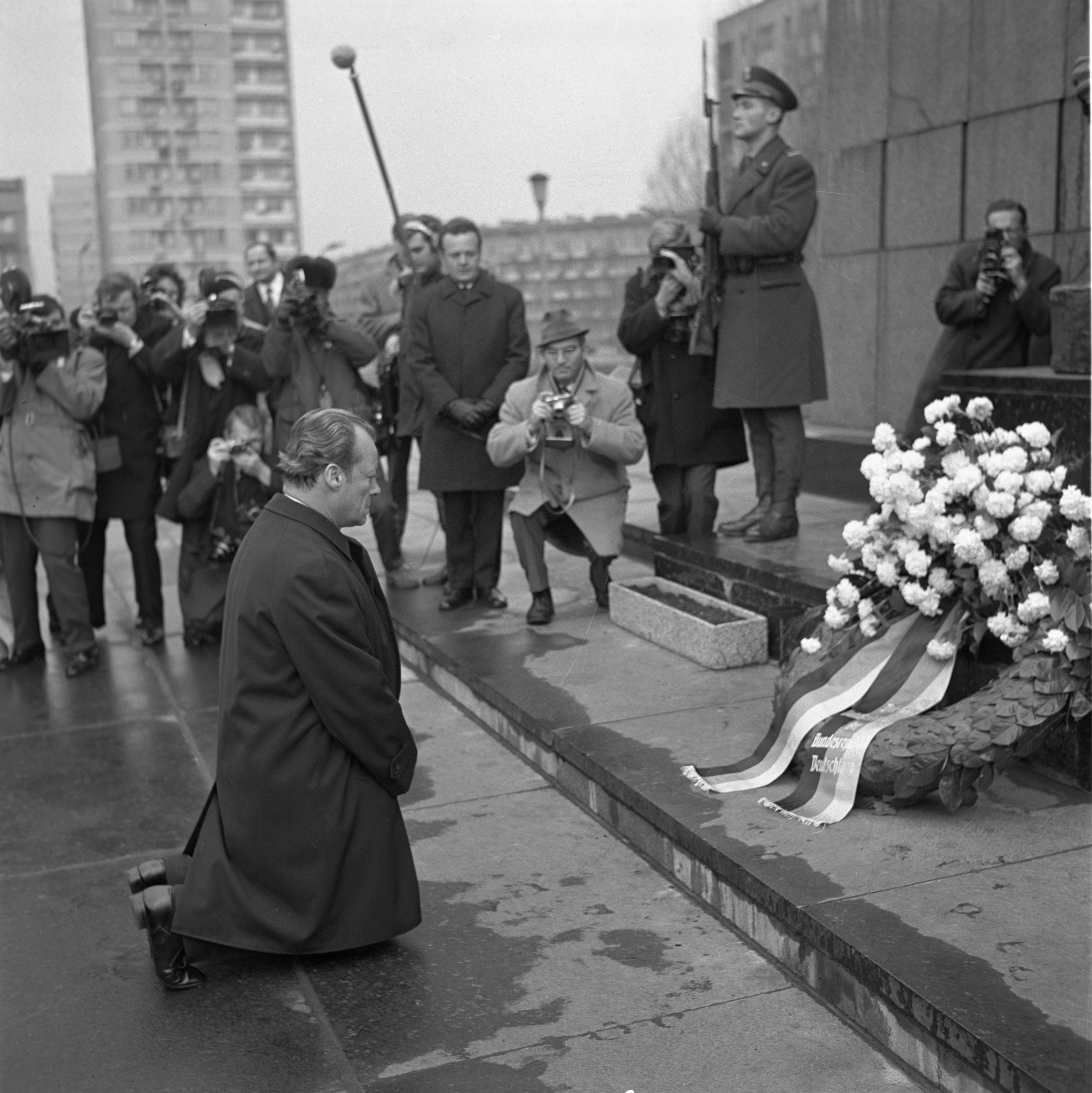 Zdjęcie archiwalne biało-czarne z 1970 roku, na którym kanclerz RFN Willy Brandt wykonuje symboliczny gest - klęka przed pomnikiem Bohaterów Getta w Warszawie, oddając hołd ofiarom Zagłady.