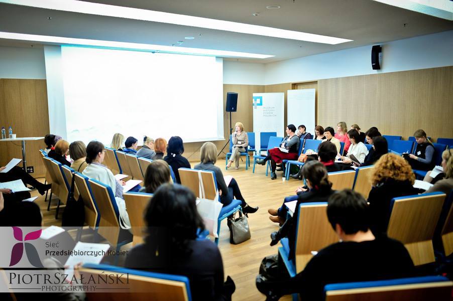 Sala konferencyjna A - zdjęcia z wydarzenia - krzesła ustawione wokół sali. Uczestnicy spotkania rozmawiają ze sobą.
