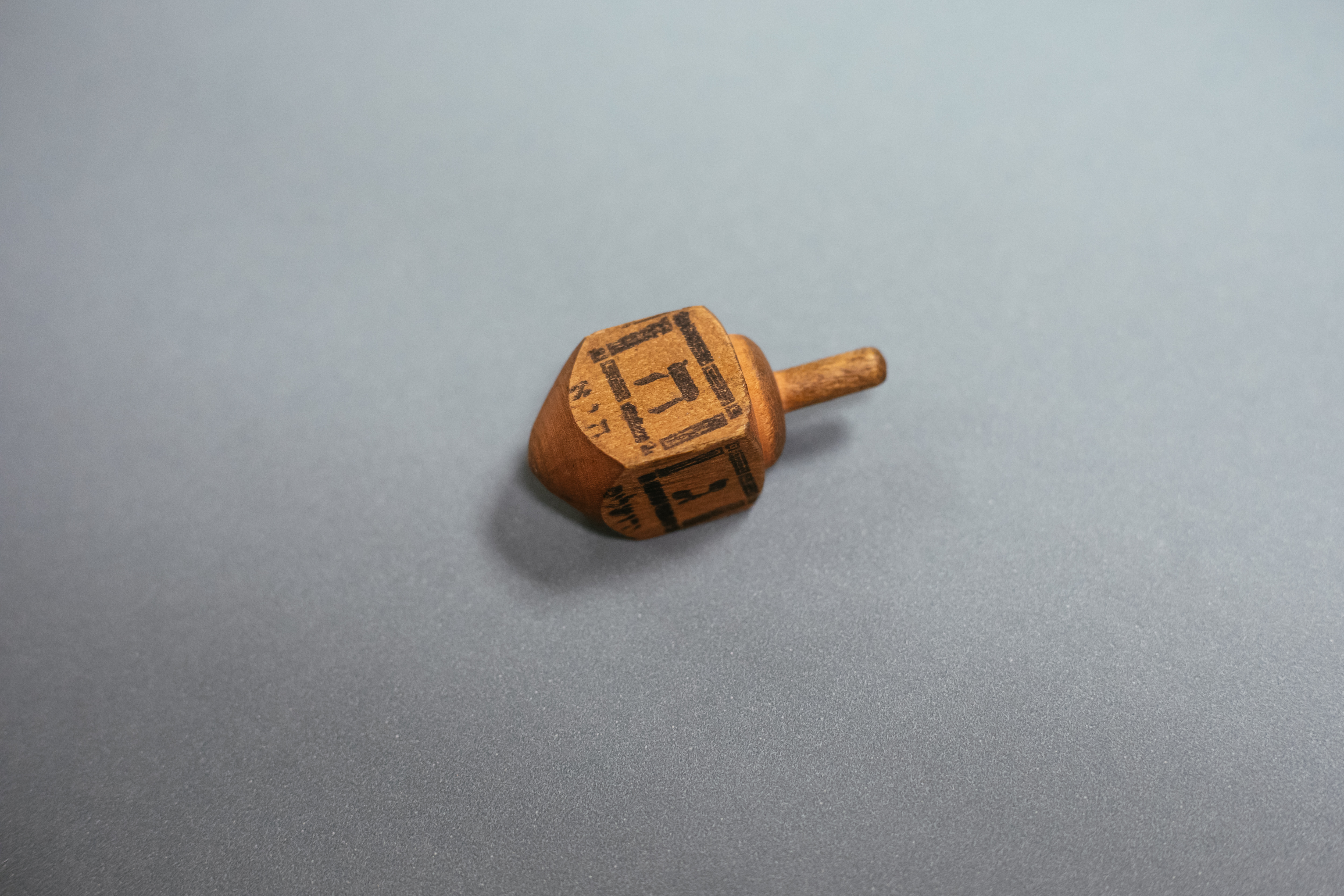 Czworoboczny bączek chanukowy (drejdel) wykonany z drewna, z literą hebrajską na każdym boku.