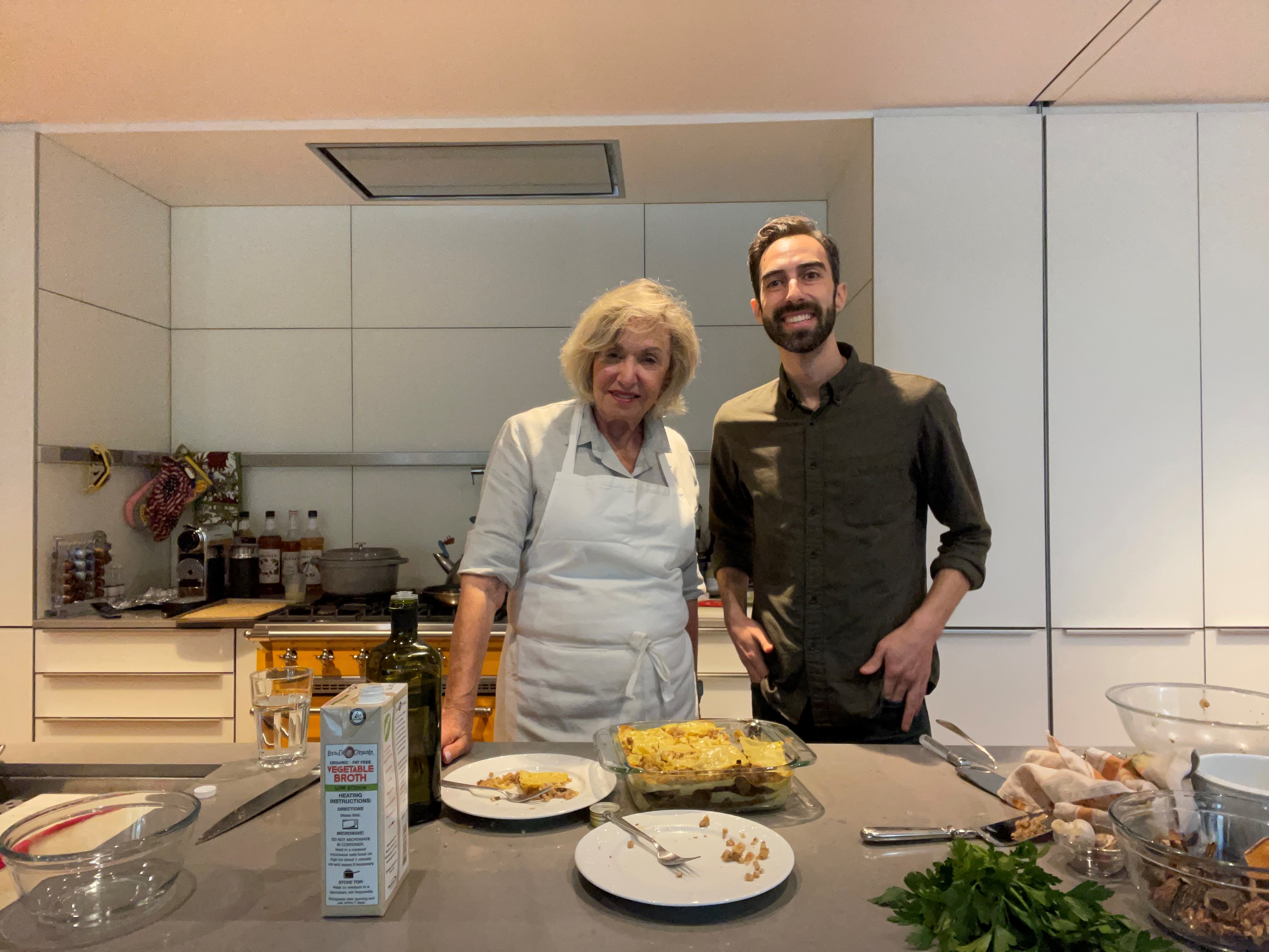 Irene and Jefrrey in a bright kitchen. Irene is blonde, older lady. Jeffrey is a young man with beard.