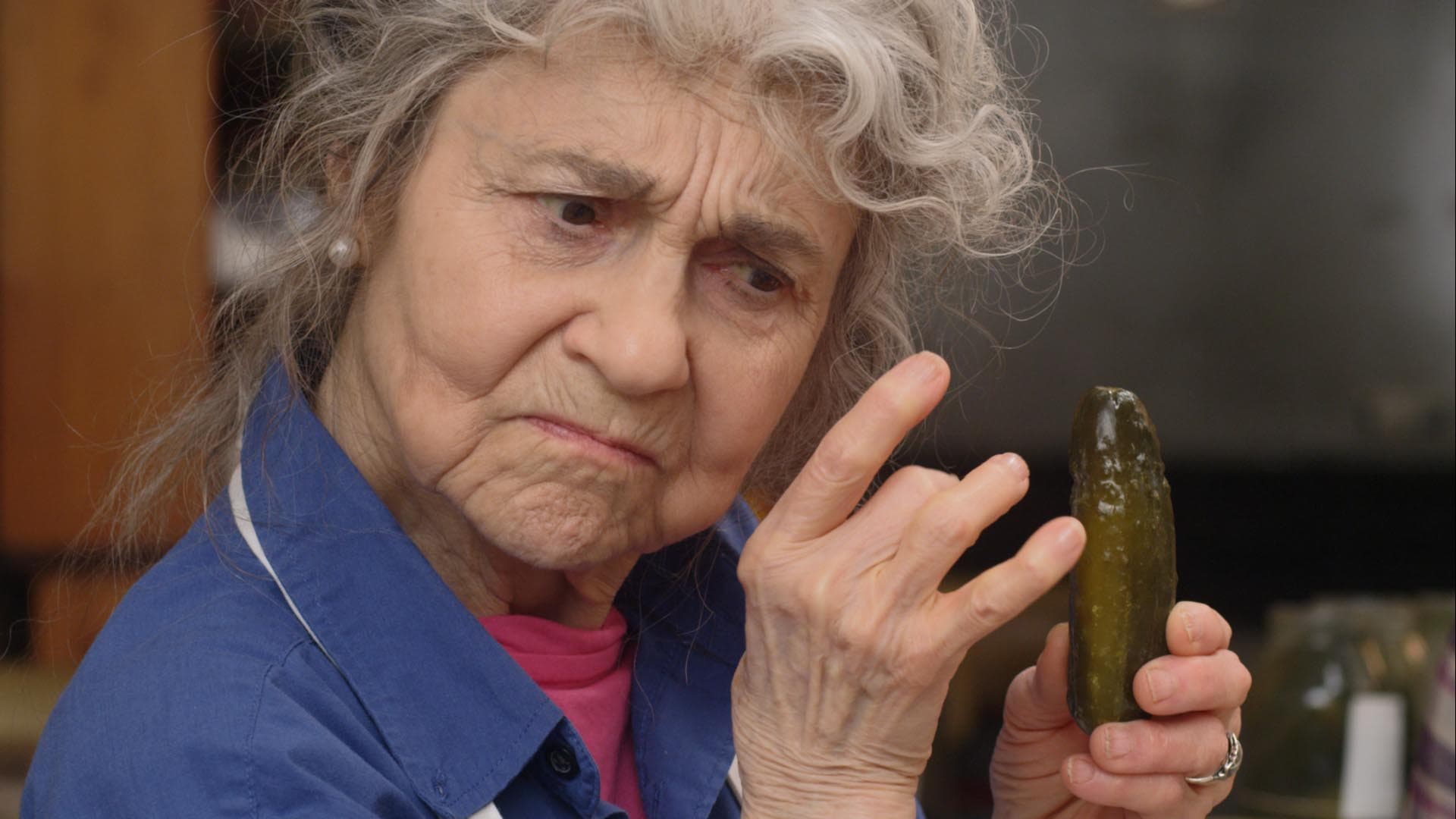Kadr z filmu "Przepis na kiszone ogórki". Babcia, jedna z bohaterek filmu, trzyma jednego ogórka.