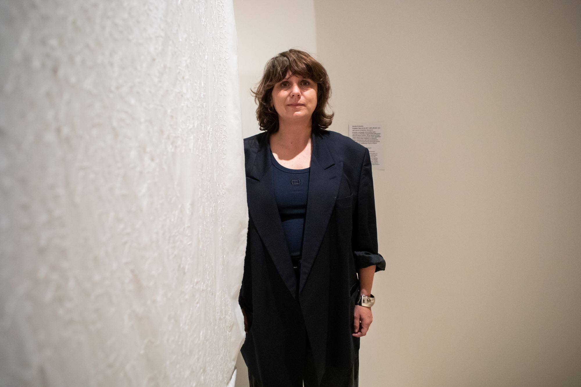 Monika Drożyńska stoi przy swojej tkaninie z serii "Obrusy".