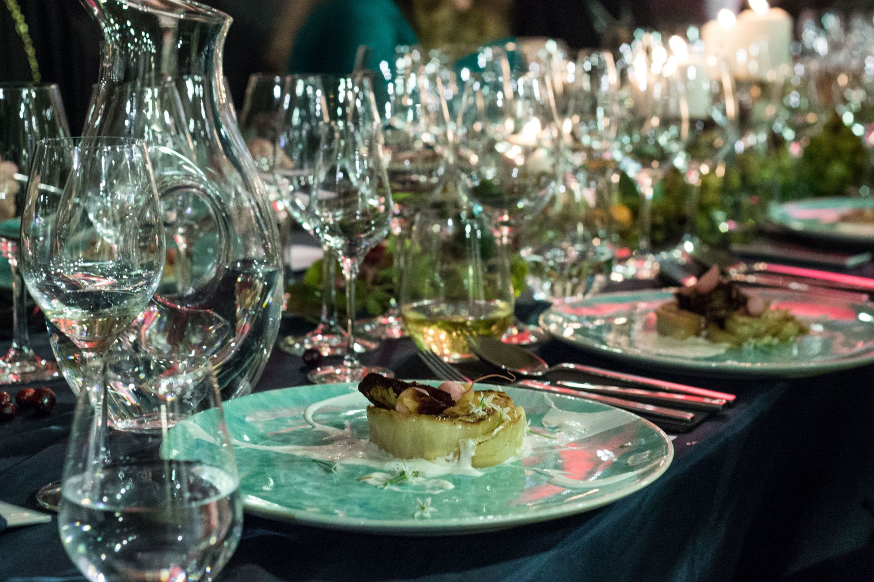 Kieliszki na stole i dania na talerzach podczas kolacji szabatowej.