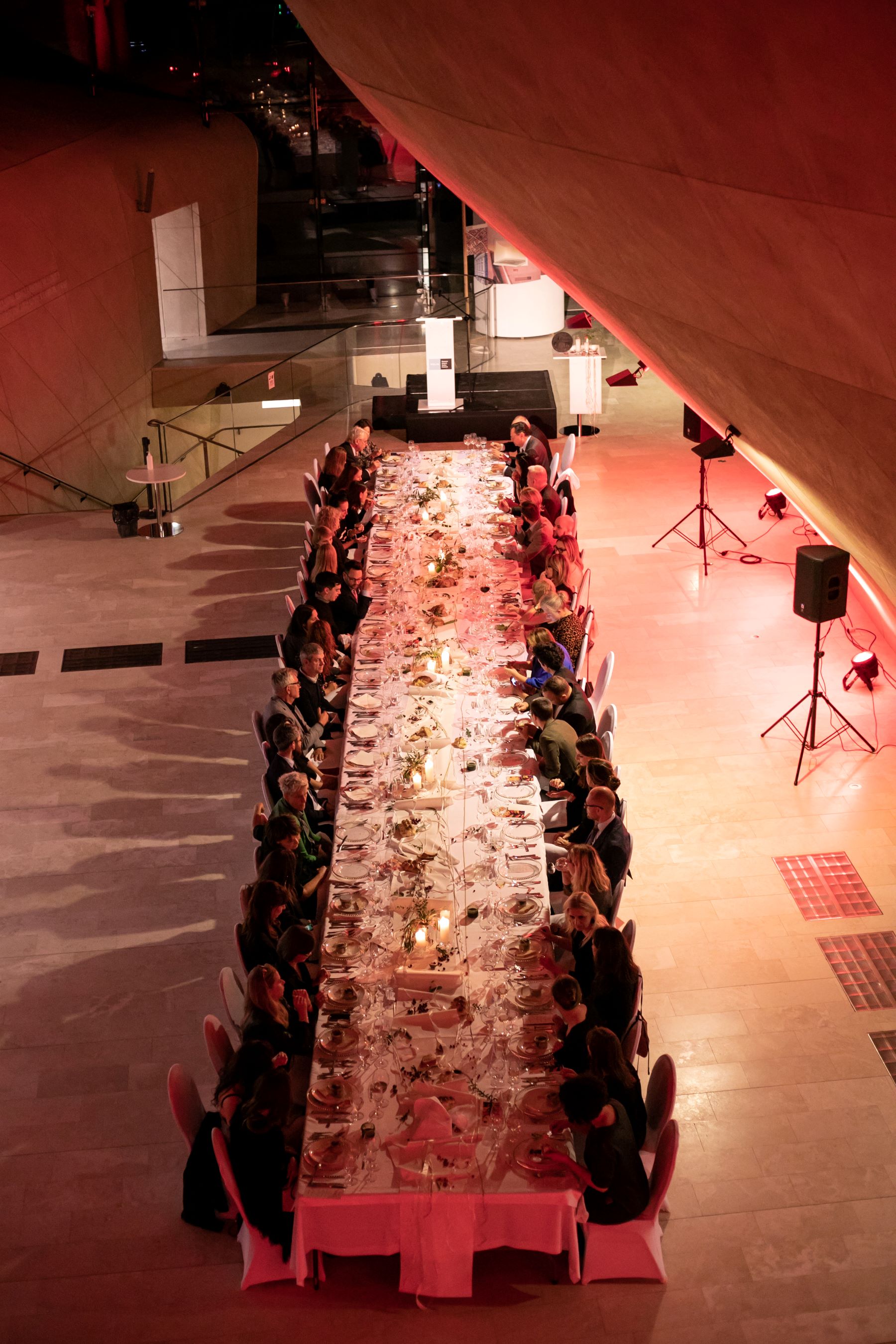 Goście zaproszeni na uroczystość z okazji wręczenia Nagrody Europa Nostra siedzą przy stole w holu głównym Muzeum POLIN.