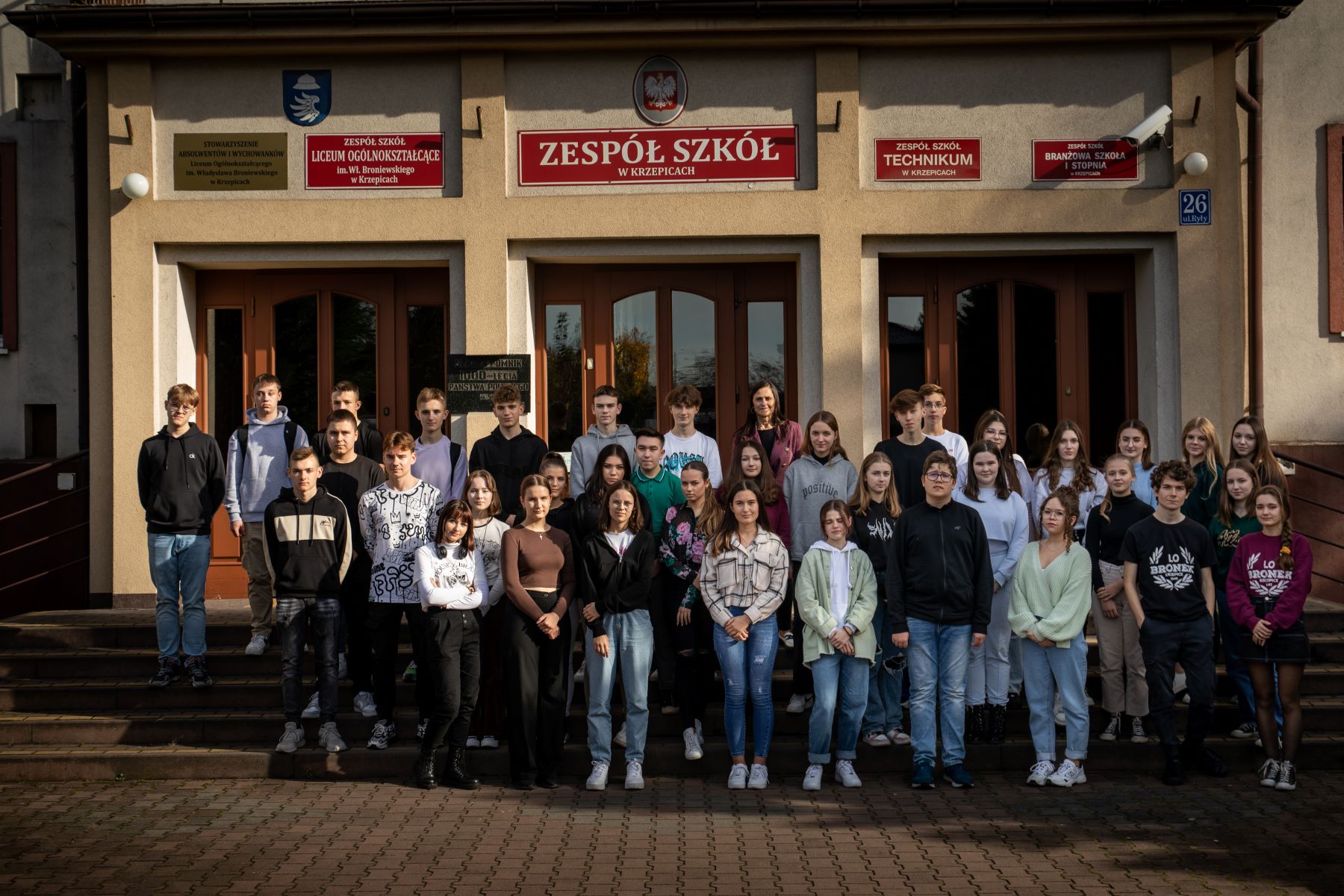 Uczniowie Zespołu Szkół w Krzepicach stoją przed szkołą.