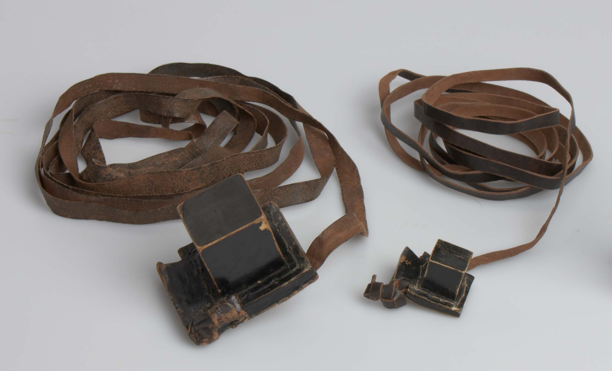Filakterie ze zbiorów Muzeum POLIN - dwa czarne skórzane pudełeczka, w których znajdują się cztery ustępy Tory.