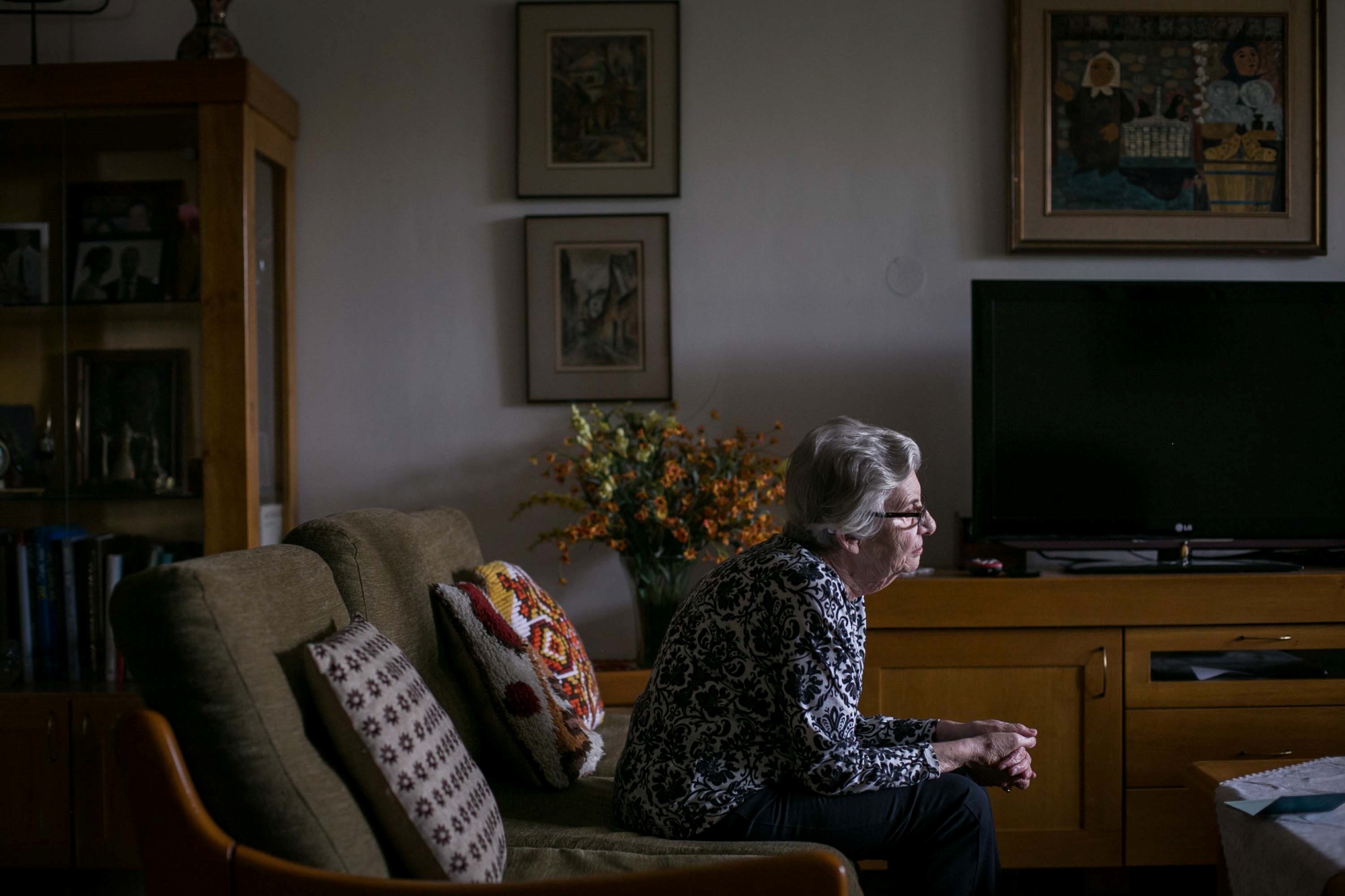 Janina Pogonowska-Goldghar siedzi na kanapie w salonie swojego mieszkania.
