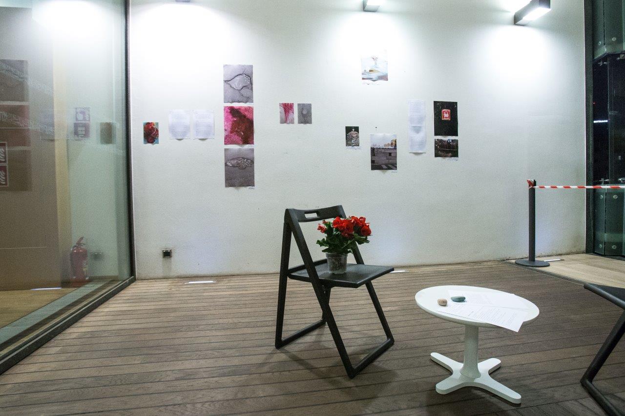 Instalacja, Tetiana Bohuslavska, Warszawa 2022, krzesło, na nim bukiet, przed nim niski biały stolik, w tle na białek ścianie kompozycja ze zdjęć