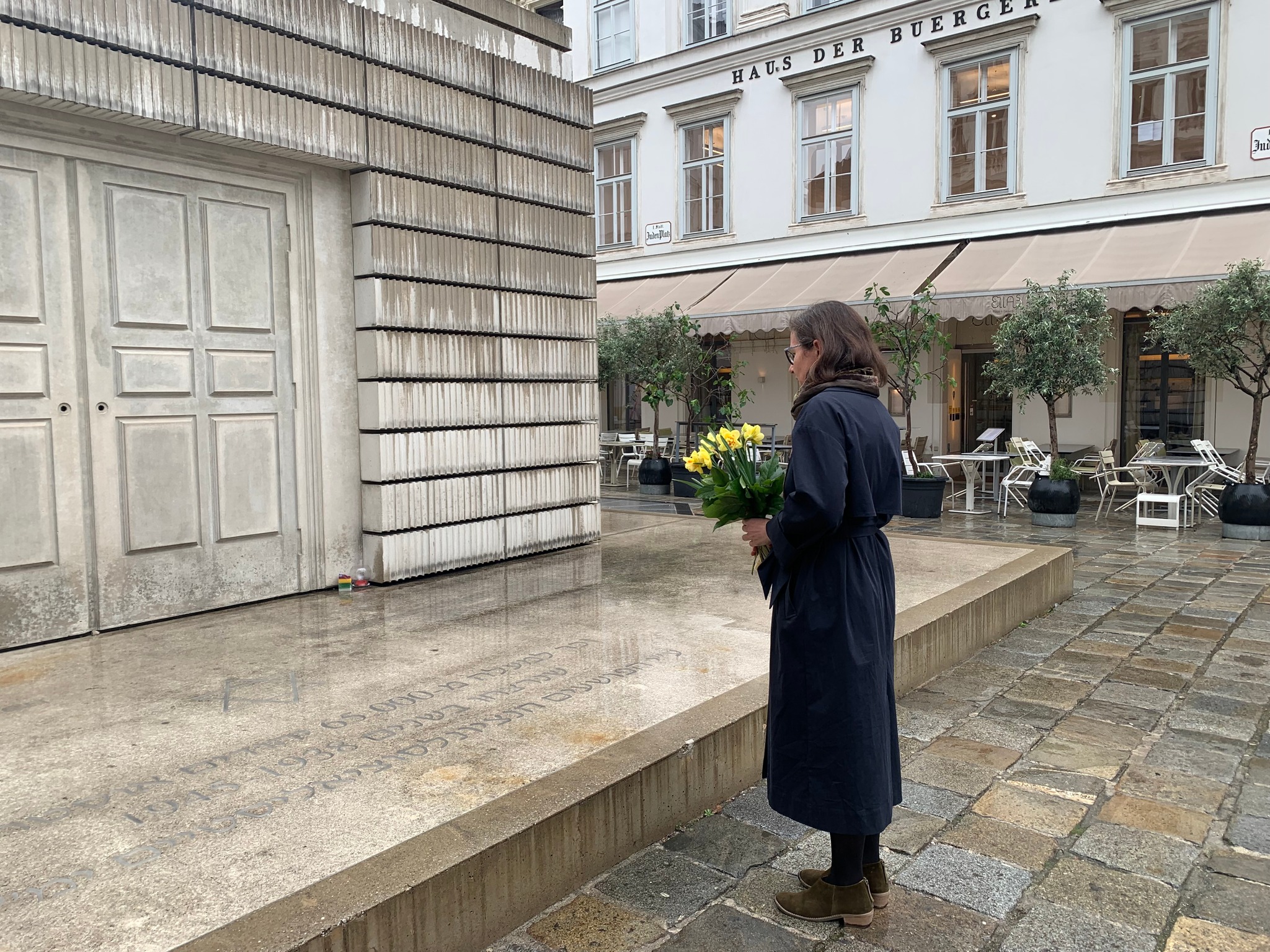 Vienna, 79 th anniversary of the outbreak of the Warsaw Ghetto Uprising. A woman holds a bouquet of daffodils and stands in front of the monument.