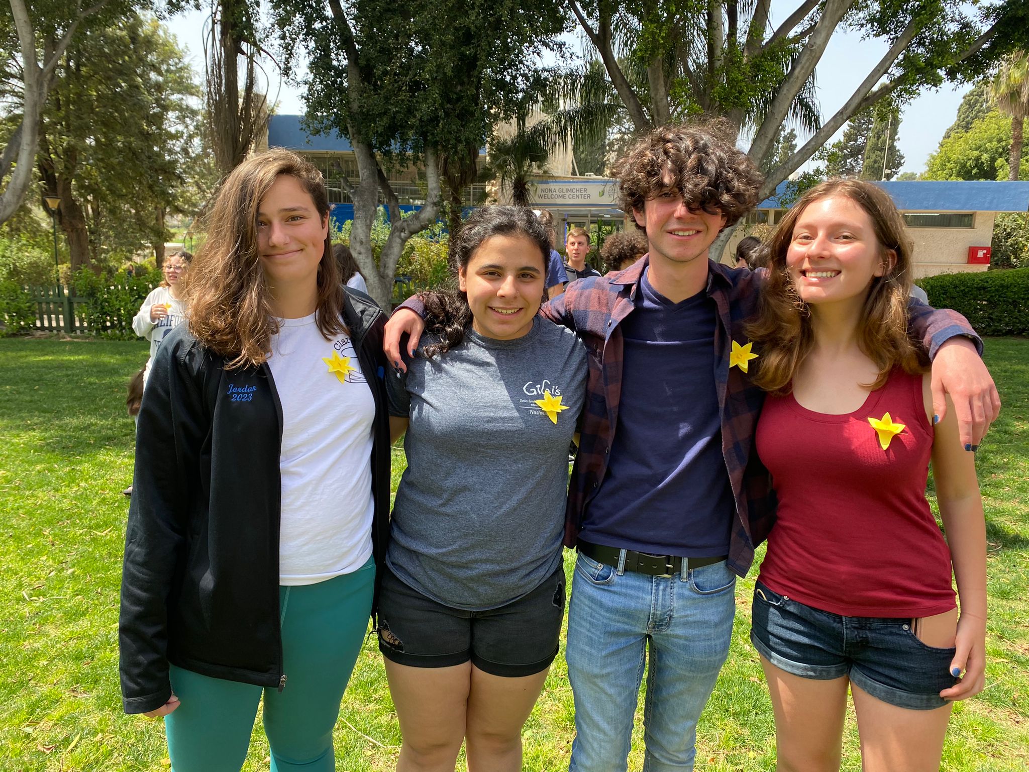 Sunny day in Israel. Three girls and one boy are standing next to each other. They are wearing paper daffodils on their clothes.