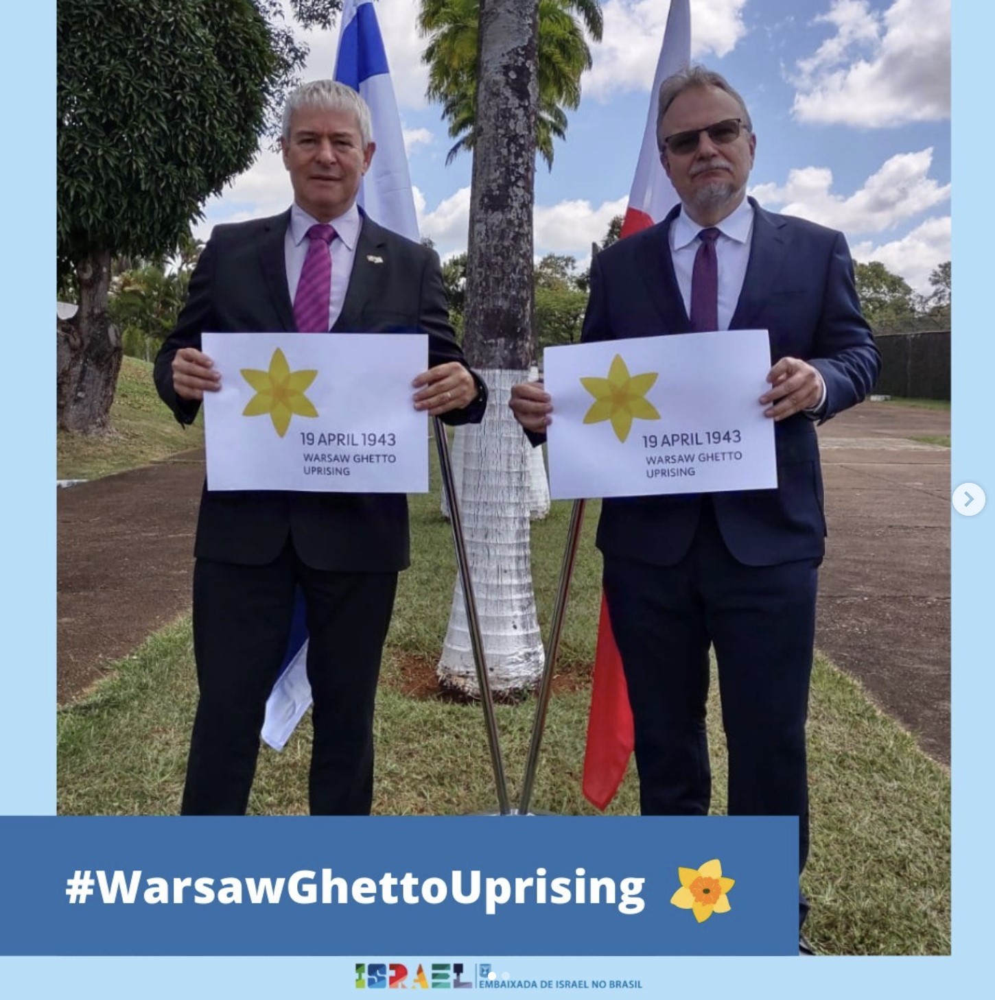 Two men from Israeli embassy in Brasil are standing with Warsaw Ghetto Uprising Campaign posters in English.