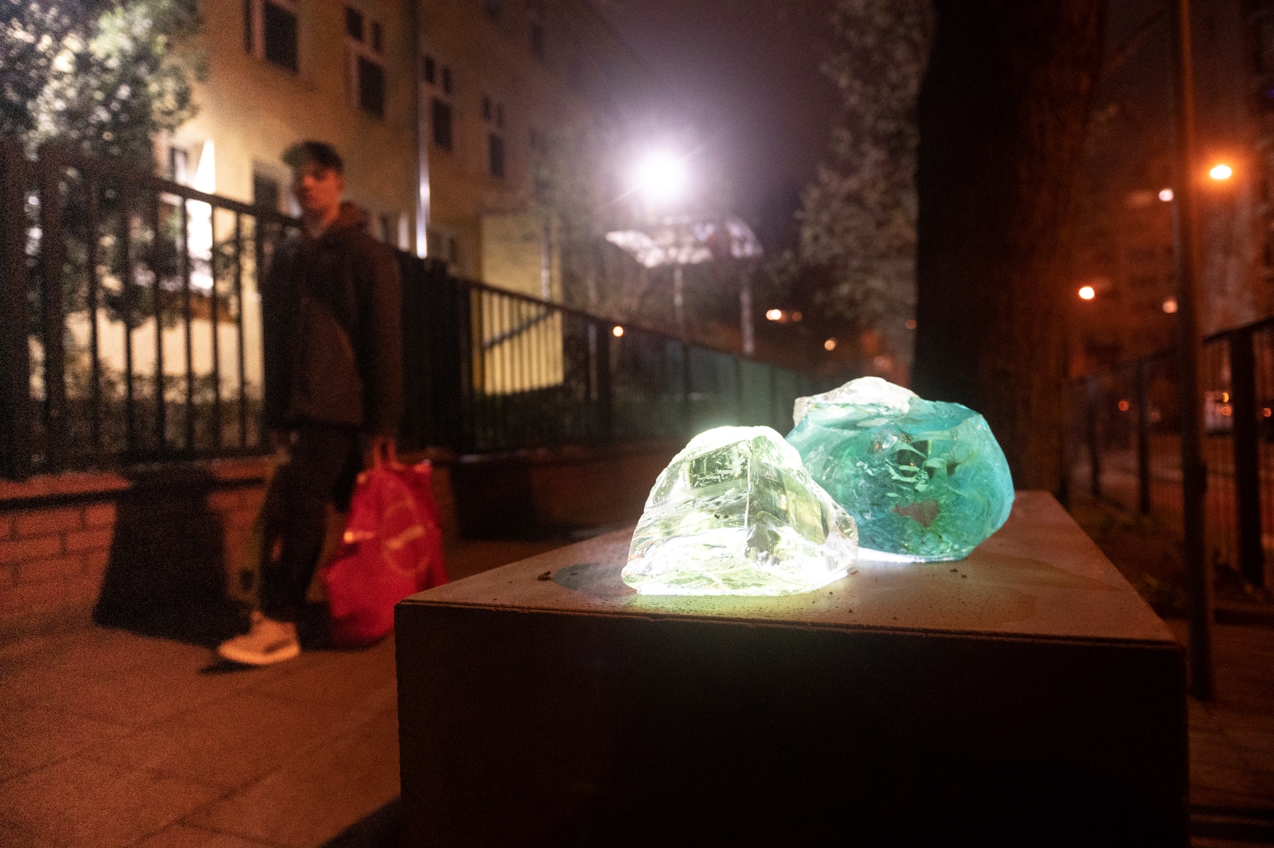 Na postumencie przymocowane dwa świecące kamienie - biały i zielony - symbolizujące kryjówki getta warszawskiego.