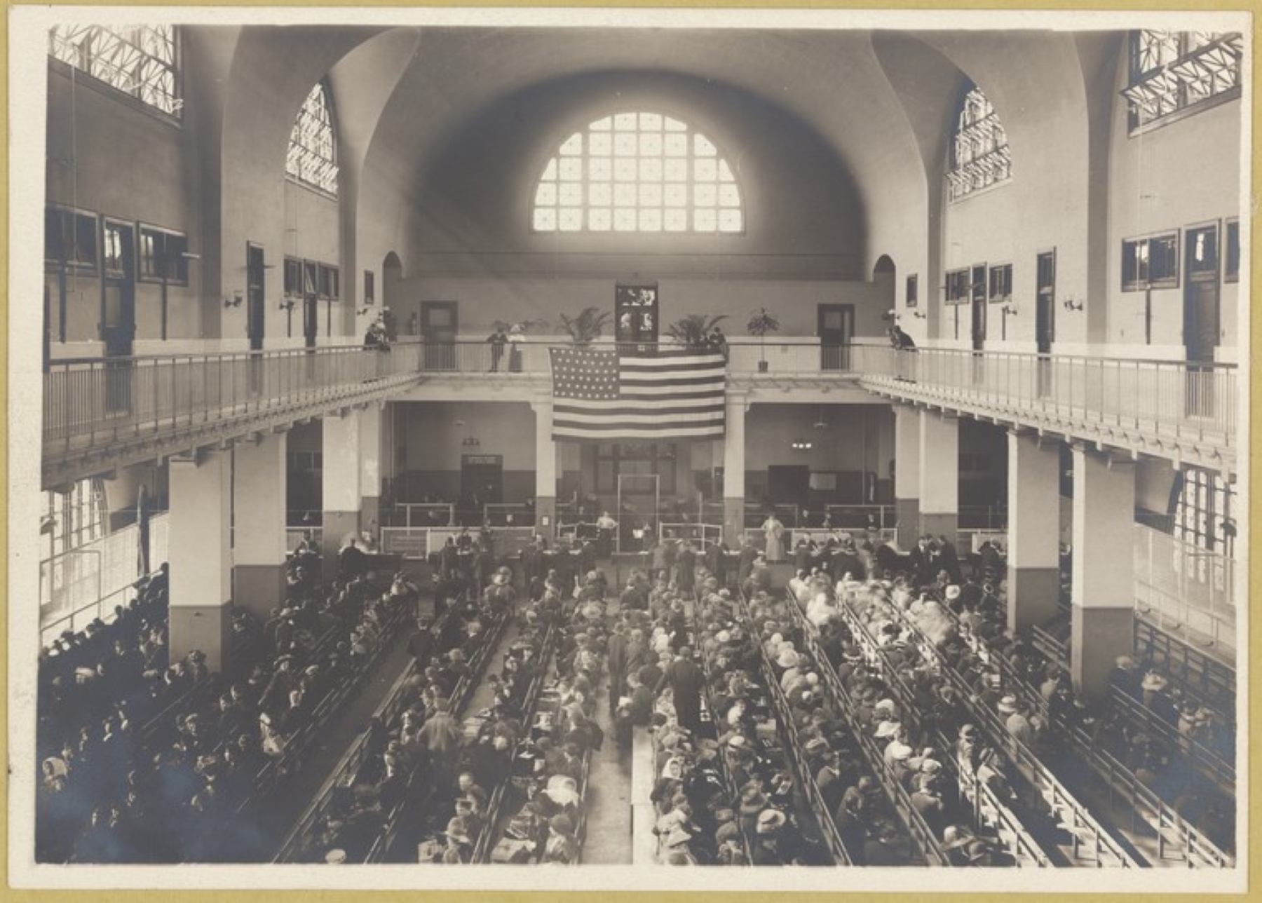 Grupa ludzi siedzi w sali wykładowej. Na górze wisi flaga USA. Zdjęcie archiwalne.
