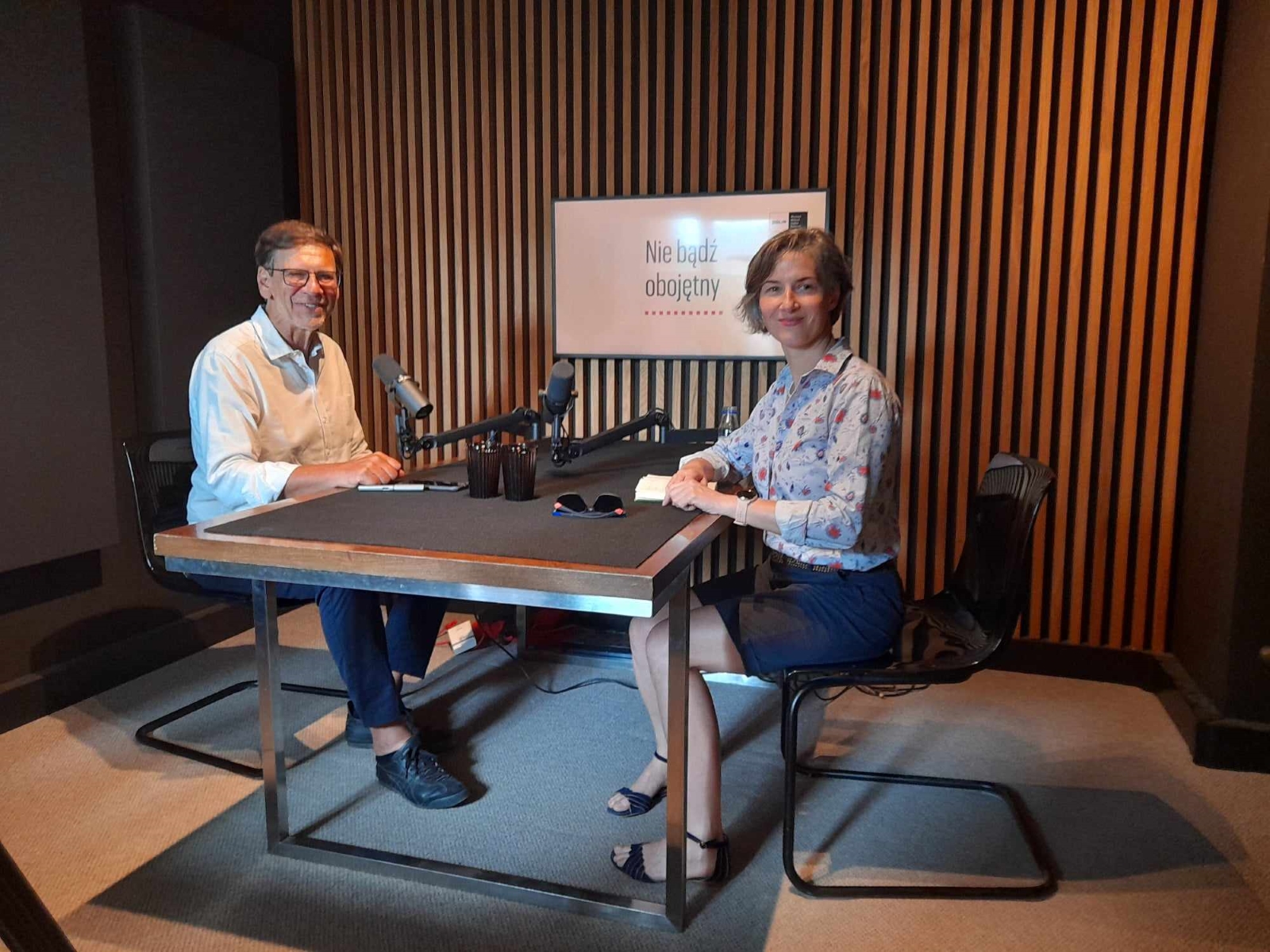 Karolina Wigura i Jacek Santorski siedzą przy mikrofonach w studiu podcastowym.