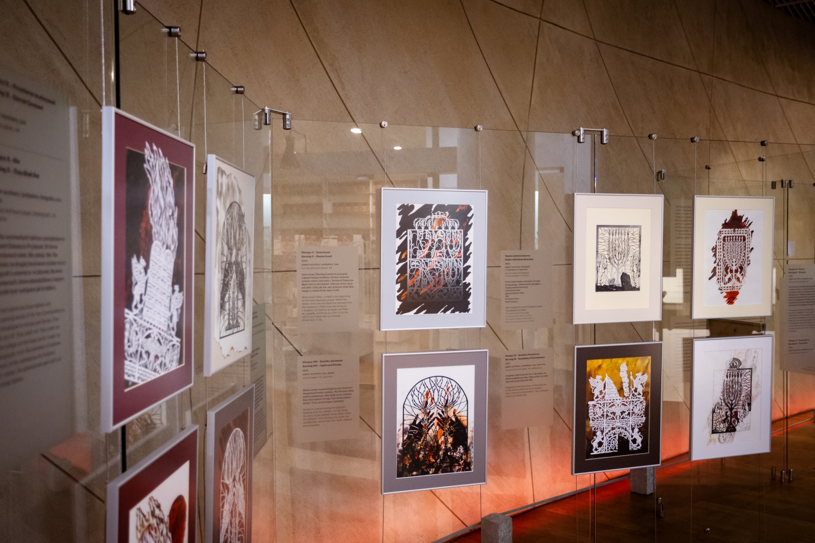 Na szklanych ściankach wiszą prace Moniki Krajewskiej prezentowane na wystawie "Płonące".