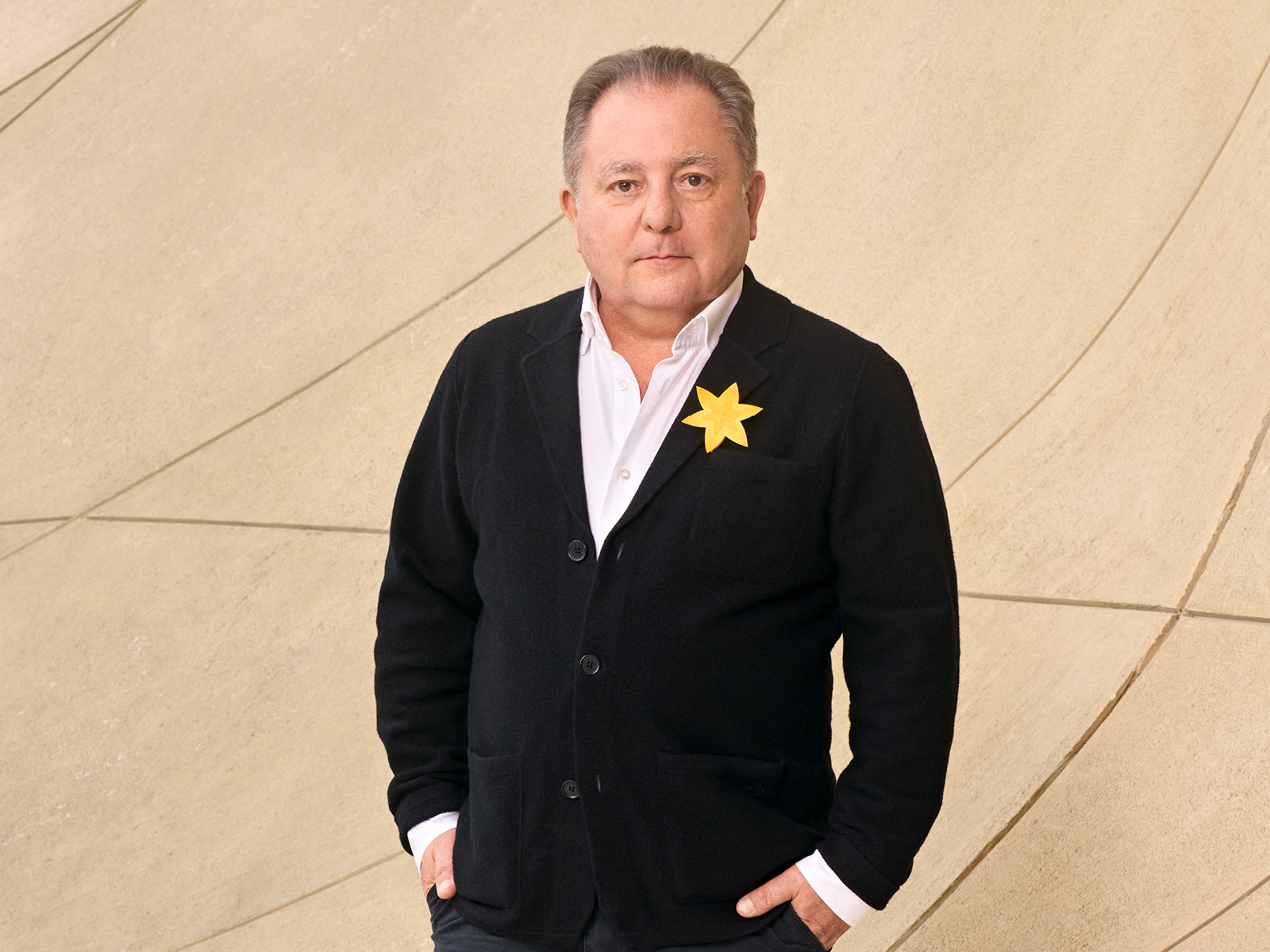 Robert Makłowicz ma przypięty żonkil do czarnego swetra.