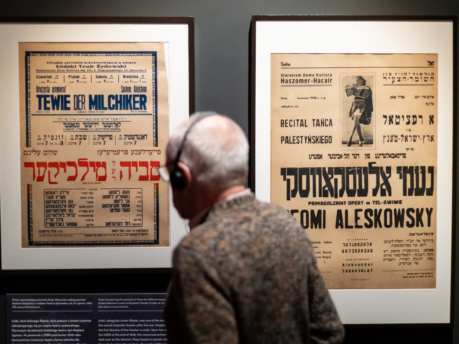 Mężczyzna zwiedza wystawę "1945. Nie koniec, nie początek". Stoi przy plakatach zapowiadających premierę Tewje Mleczarza.