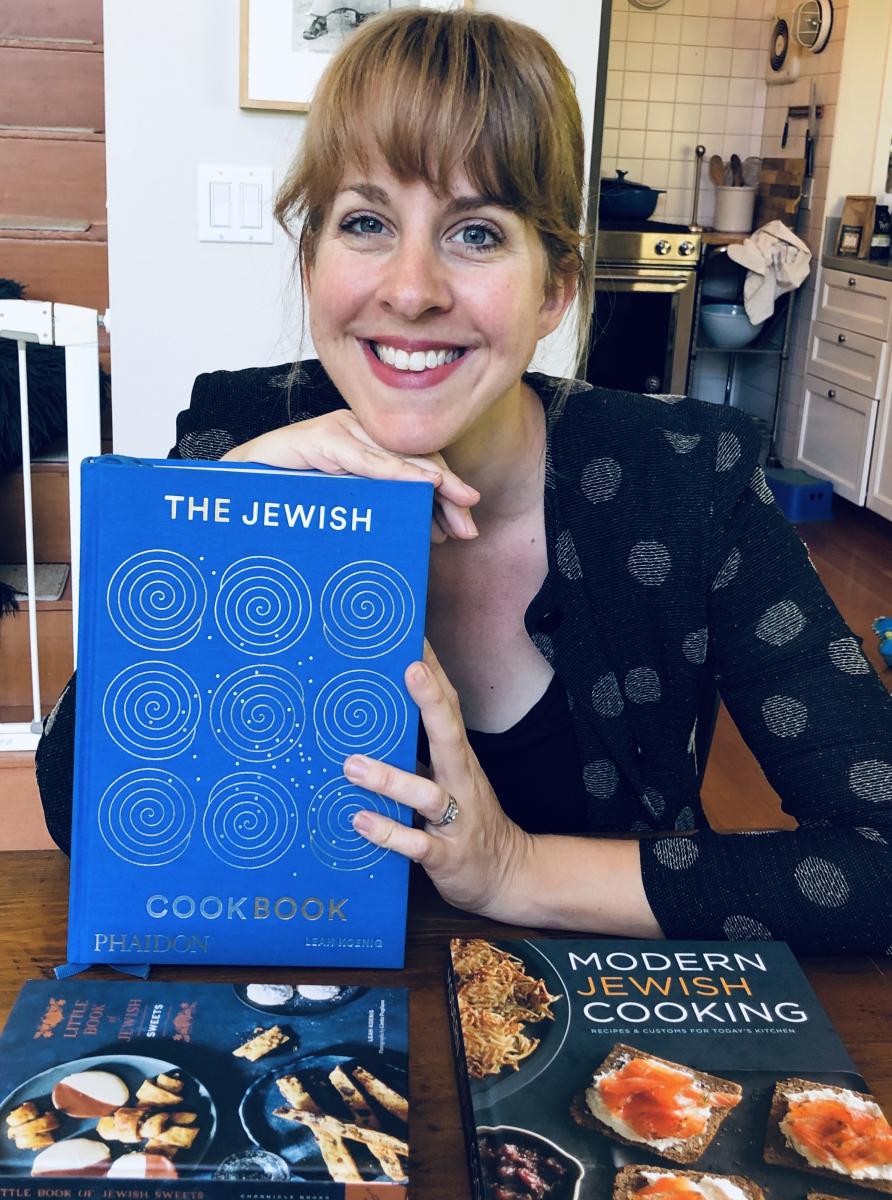 Na zdjęciu Leah Koenig, trzyma przed sobą najnowszą swoją książkę pt. "The Jewish Cookbook"