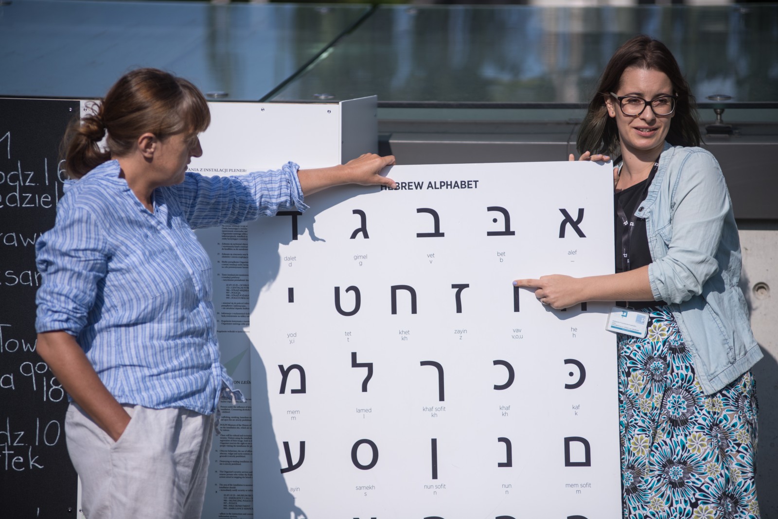 Hebrajski na trawie - dwie kobiety pokazują na planszy litery hebrajskie.