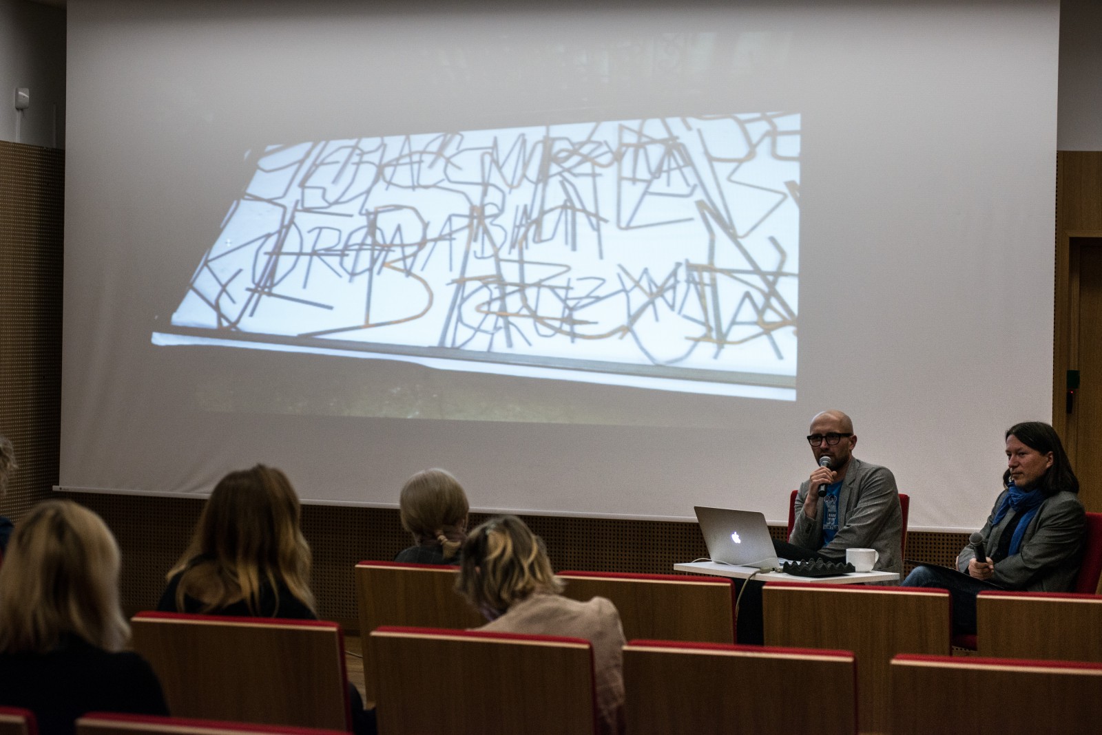 W sali Muzeum Polin kilka osób ogląda prezentację slajdów artysty Huberta Czerepoka 