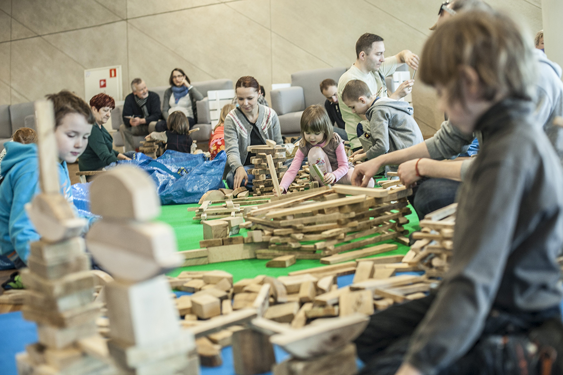 Dzieci budują zamek z pociętych kawałków drewna.