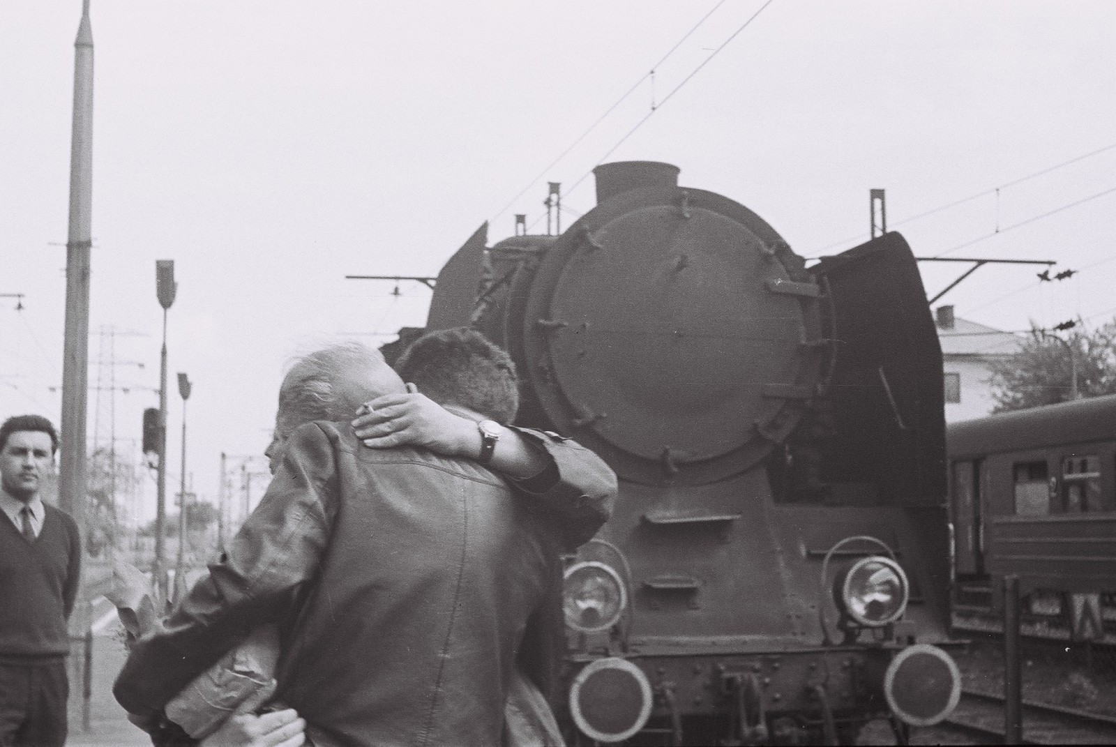 Zdjęcie archiwalne. Dwoje ludzi przytula się do siebie. W tle lokomotywa.