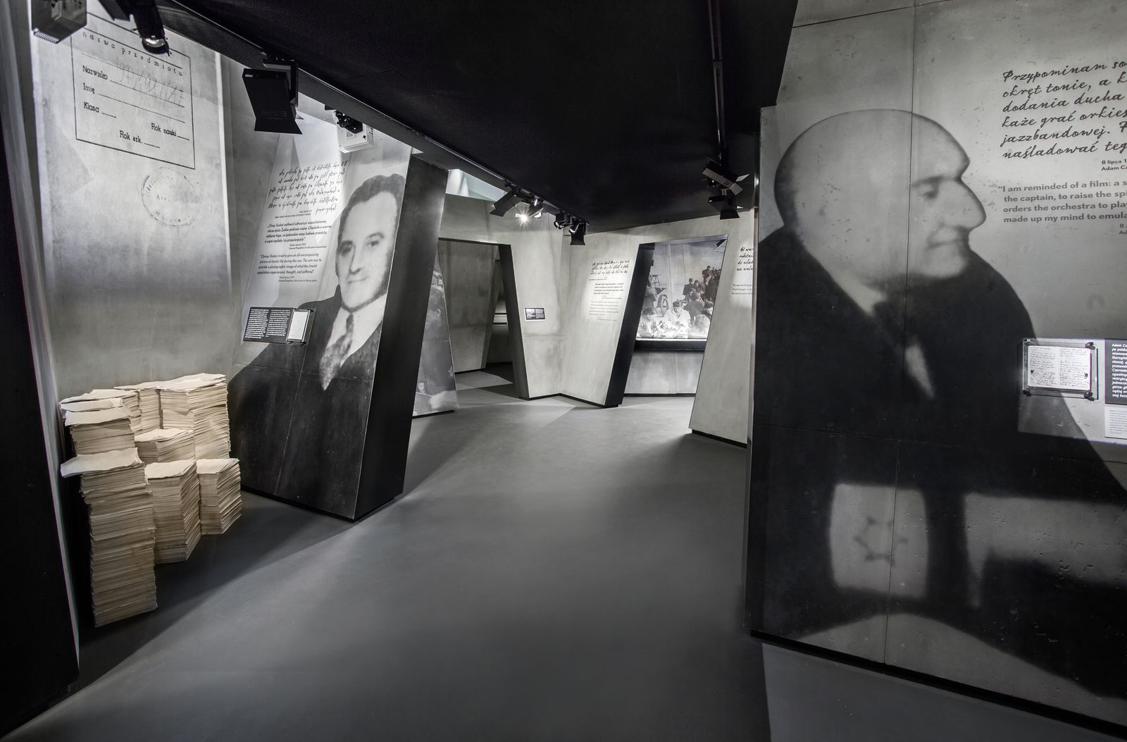 Galeria "Zagłada" na wystawie stałej w Muzeum Polin. Stos dokumentów i portret oraz wypowiedź Adama Czerniakowa.