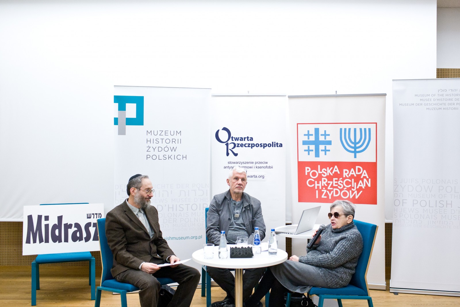 Troje uczestników dyskusji "Uwierzyć w muzeum" siedzi przy stoliku.