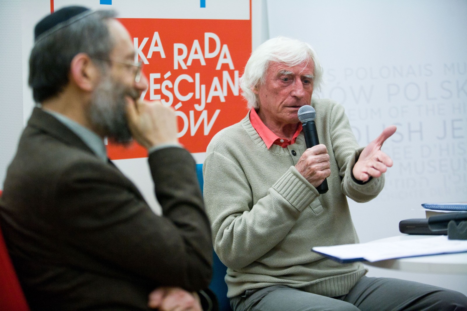 Dwaj paneliści siedzą przy stoliku podczas dyskusji "Uwierzyć w muzeum" w 2014 r.