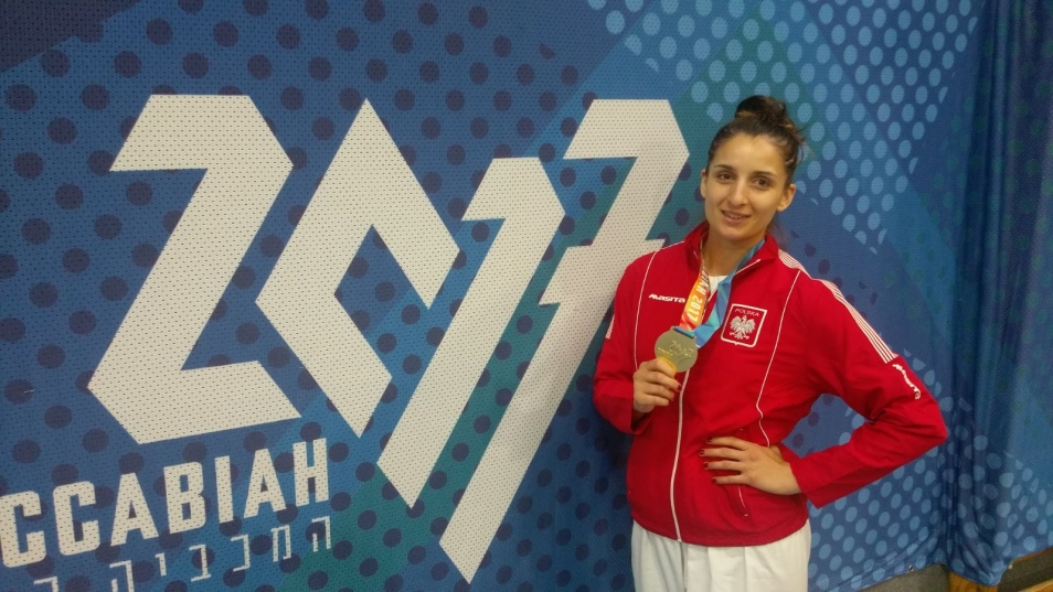 Na obrazie widzimy kobietę trzymającą w dłoni medal. 