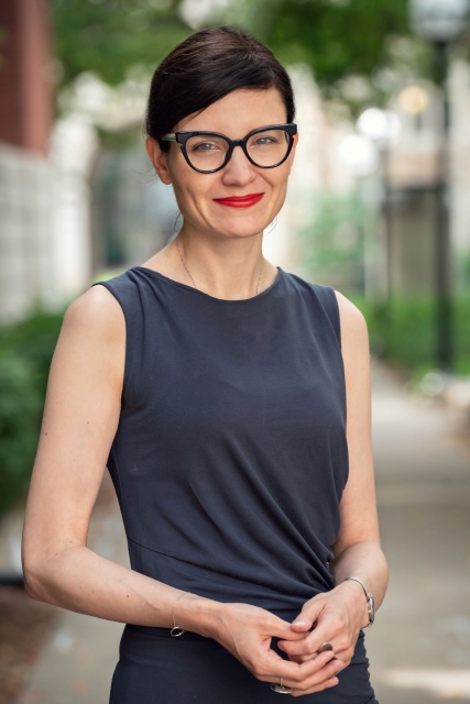 Karolina Szymaniak, prelegentka na spotkaniu POLIN Book Talks. Uśmiechnięta gładko uczesana brunetka z pomalowanymi na czerwono ustami.