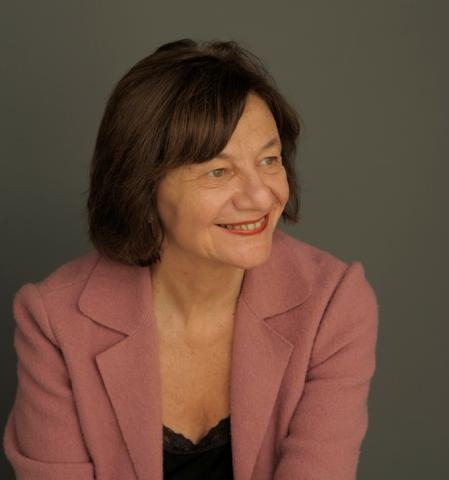 Eva Hoffman - uśmiechnięta brunetka w średnim wieku. Jest ubrana w czarną bluzkę i różowy żakiet.