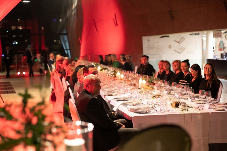 Uroczystość wręczenia Nagrody Europa Nostra dla Muzeum POLIN za TISZ Festiwal. W holu głównym muzeum, przy stole siedzą zaproszeni goście.