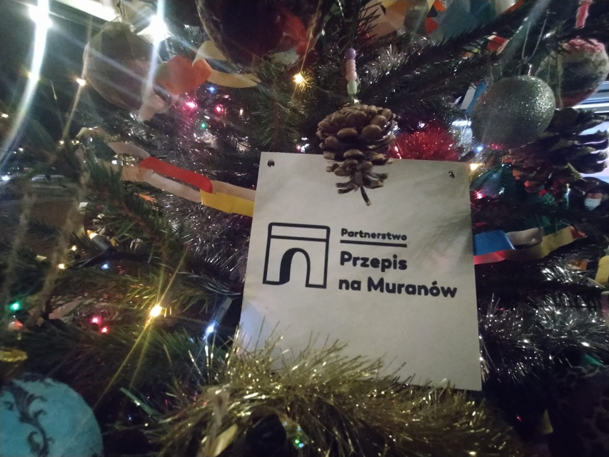 Wśród ozdób choinkowych biały kartonik z napisem Przepis na Muranów.