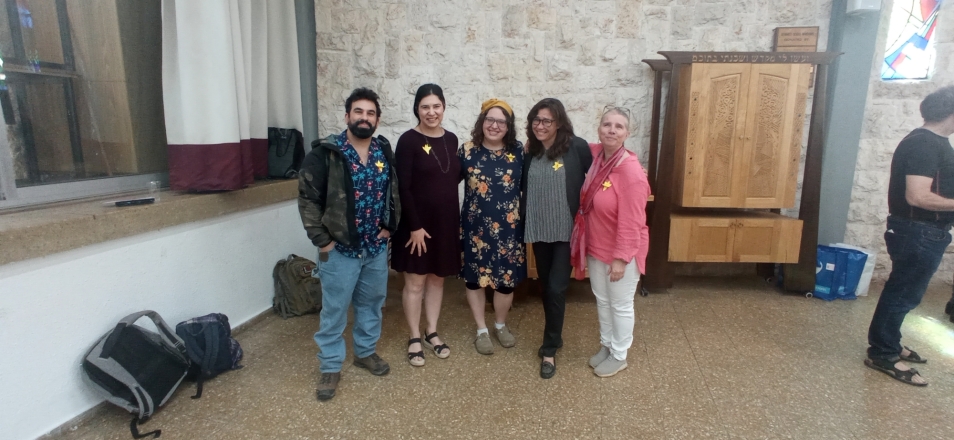 Five teachers from Israel are standing in some room. They have paper daffodils pinned to their clothes.