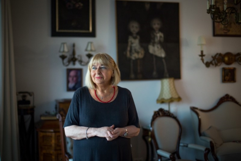 Elżbieta Ficowska stoi w swoim mieszkaniu pełnym antyków.