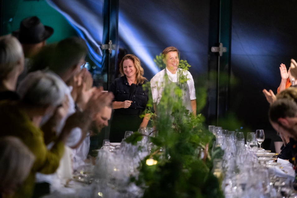 Sabina Francuz standing by a table with theguests of shabbat dinner at POLIN Museum during TISH Festival.