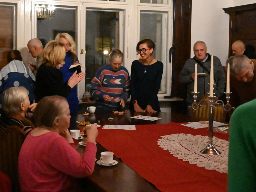 Dagmara Mańka-Wizor stoi przy stole z uczestnikami spotkania chanukowego.
