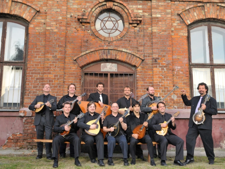 Members of the Ger Mandolin Orchestra sit or stand, holding mandolins in their hands.