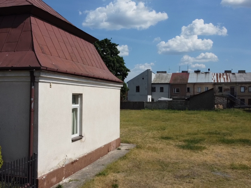 Kadr z etiudy "Kałuszyn: sąsiedzkie spotkania". Dom jednorodzinny. W tle parę szeregówek.