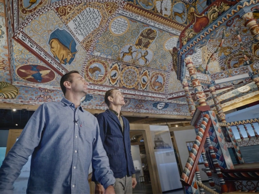 Adam Balcer i Paweł Sulik, prowadzący cykl Planeta POLIN, stoją przy rekonstrukcji synagogi z Gwoźdźca na wystawie stałej.