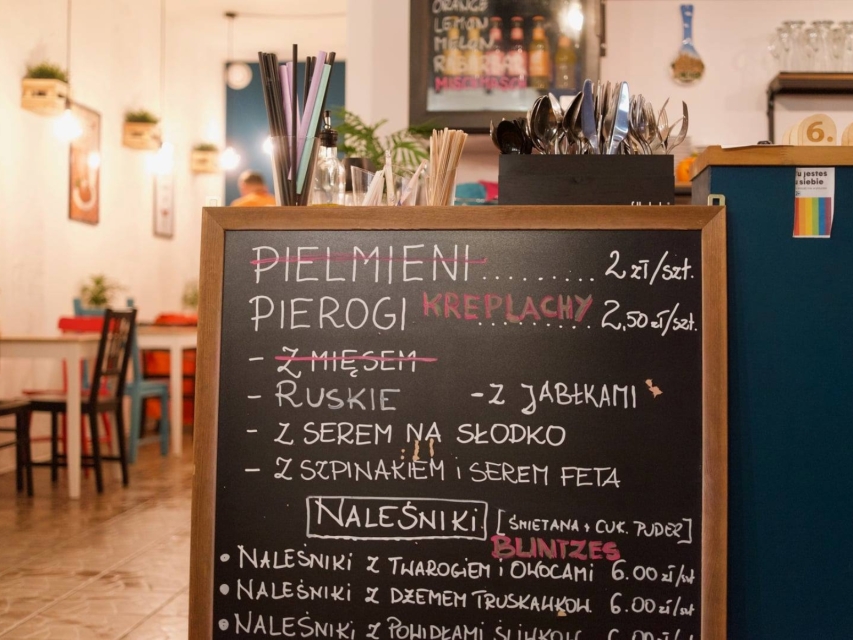 Tablica w barze w wypisanym menu. W wykazie np. pierogi ruskie, z jabłkami, z serem na słodko, ze szpinakiem i serem feta oraz naleśniki.