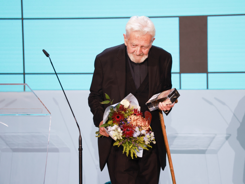 Finał konkursu Nagroda POLIN 2024. Ksiądz Adam Boniecki z kwiatami i statuetką.