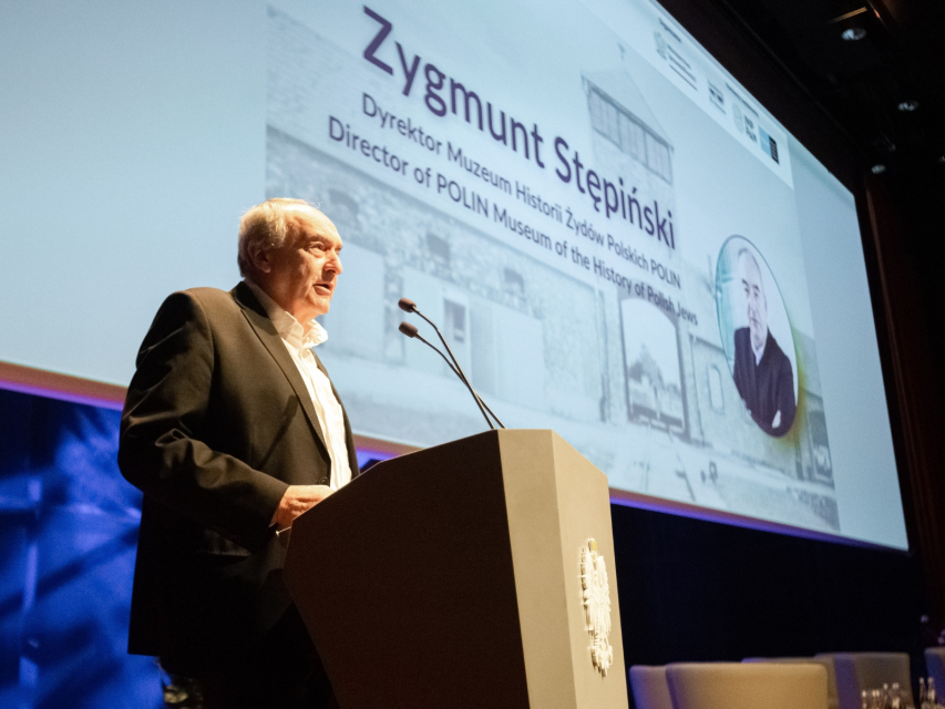Zygmunt Stępiński stoi przy mównicy w Audytorium podczas konferencji Muzeum POLIN i Ministerstwa Sprawiedliwości.