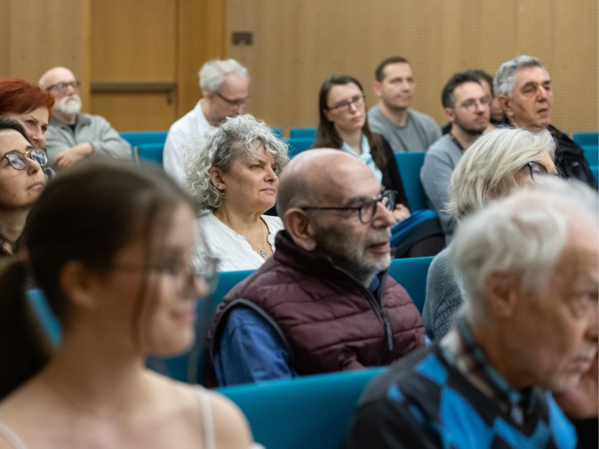 Uczestniczki i uczestnicy spotkania z autorkami i autorami czasopisma "Plotkies" siedzą w sali konferencyjnej.