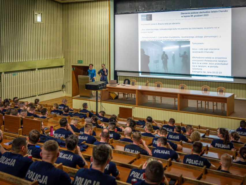 Grupa policjantek i policjantów siedzi na sali wykładowej podczas szkolenia w ramach projektu BETAAEC.