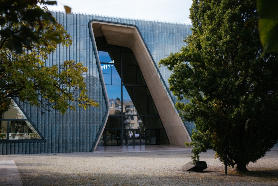 Budynek Muzeum POLIN wśród zielonych drzew.