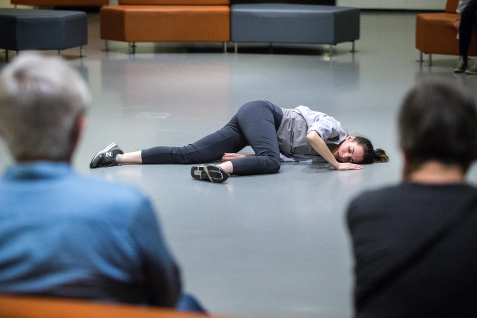A woman in a white shirt is lying on the floor.