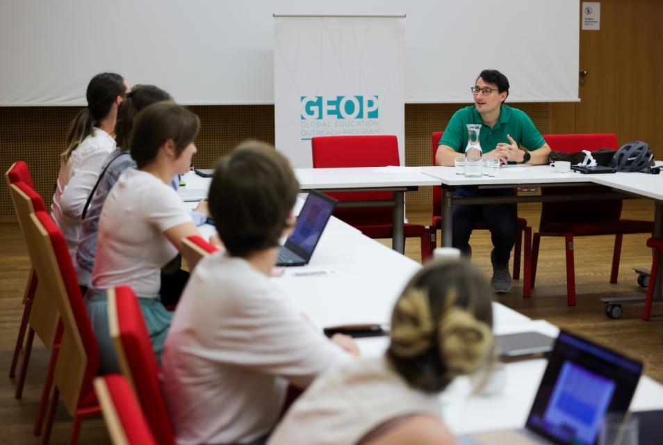 Prowadzący i uczestniczki Szkoły letniej siedzą przy stole w sali konferencyjnej.
