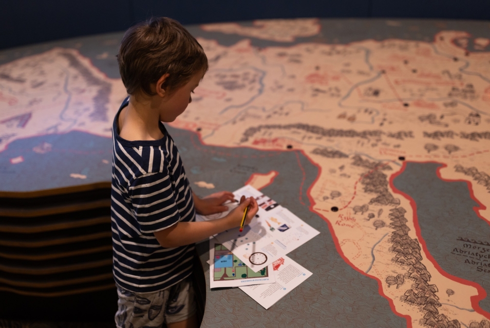 The boy fills out the worksheets at the Core Exhibition. The worksheets are located at the display showing the map.